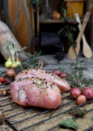 Fresh raw chicken breast with herbs and spices in the kitchenの写真素材