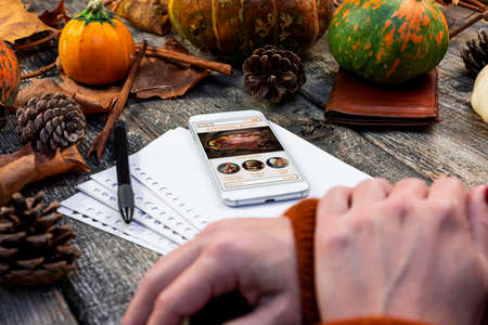 Touchscreen smartphone with online cooking blog on the screen at rustic table in the kitchen. Thanksgiving recipe. Autumn concept cookingの写真素材