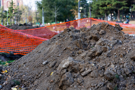 Pile of dirt at the construction site with safety orange net in the background