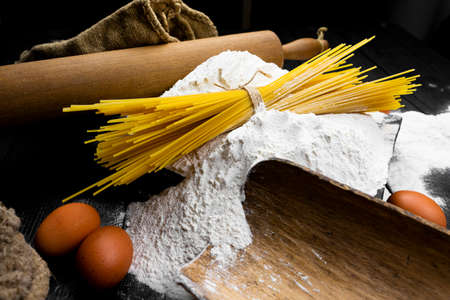 Fresh uncooked Spaghetti and pasta ingredients on a rustic table. Italian cusine and cooking conceptの写真素材