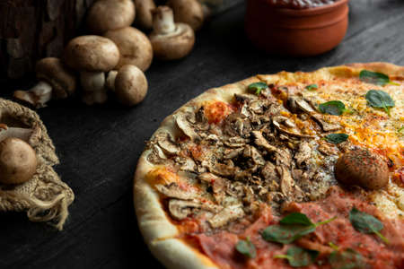 Italian Pizza Four Seasons (Pizza Quattro Stagioni) with different ingredients on the wooden table in the kitchen. Italian homemade recipesの写真素材