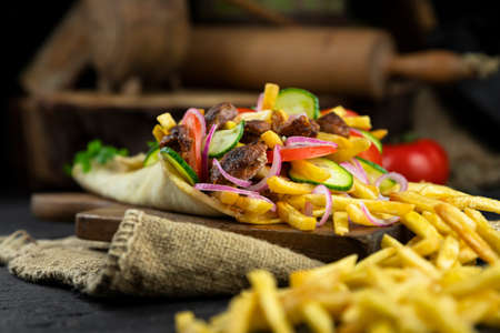 Greek gyros wrapped in pita bread on a wooden board in rustic kitchen