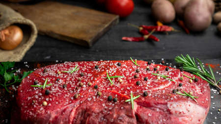 Raw beef steak seasoned with salt, pepper and fresh hearbs in the rustic kitchenの写真素材