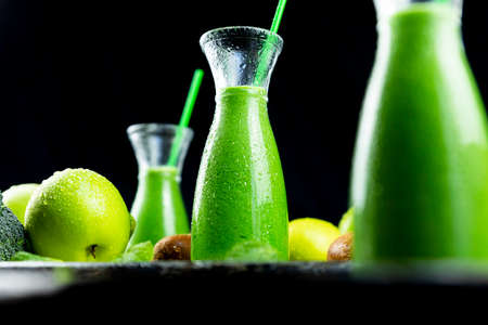 Healthy green smoothies with spinach, apple, kiwi, broccoli and mint in glass jar with fruits and vegetables on the wooden table. Detox, diet, healthy, vegetarian food conceptの写真素材