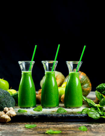 Healthy green smoothies with spinach, apple, kiwi, broccoli and mint in glass jar with fruits and vegetables on the wooden table. Detox, diet, healthy, vegetarian food conceptの写真素材