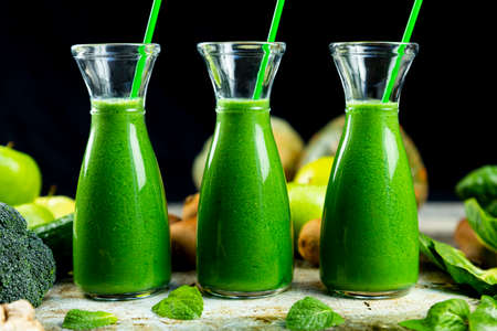 Healthy green smoothies with spinach, apple, kiwi, broccoli and mint in glass jar with fruits and vegetables on the wooden table. Detox, diet, healthy, vegetarian food conceptの写真素材