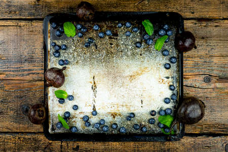 Tray with blueberries,beads and mint leaves with emty space in the middle on a rustic wooden table....