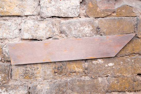 Arrow wooden sign hanging on a rustic brick wall. Emty space, add text or logoの写真素材