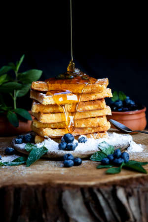 Honey pouring on Waffles with fresh blueberries on the rustic table. Freshly baked Belgian wafflesの写真素材