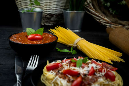 Italian spaghetti pasta with tomato sauce, parmesan cheese and basil served on the plate on rustic kitchen tableの写真素材