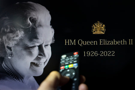 Belgrade, Serbia - September 12, 2022: Queen Elizabeth II passing. The Queen is dead at age 96. Watching news on tv about late Queen of England with remote controle in hand. Remembering and honoring her Majesty Queen Elizabeth.のeditorial素材