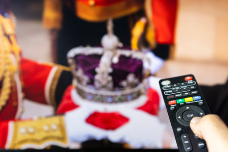 Belgrade, Serbia - September 12, 2022: The Crown of Queen Elizabeth II. The crown is thought to be worth three to five billion pounds. Watching news on tv about late Queen with remote controle in hand. Focus on the remote controle.のeditorial素材