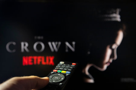 Belgrade, Serbia - September 12, 2022: Watching TV Show The Crown on Netflix with remote control in hand.  TV series is about British Royal family and Queen Elizabeth II.のeditorial素材