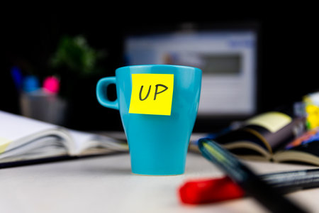 Sticky note on a coffe cup at office desk. Wake up conceptの写真素材