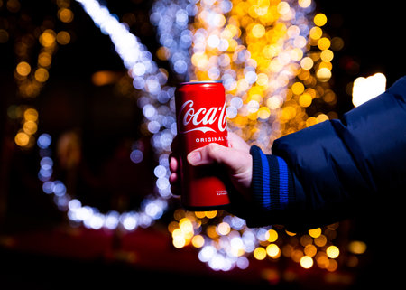 Belgrade, Serbia - January 5, 2023: Coca Cola can in hand with Christmas lights and decoration in...