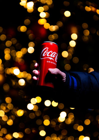 Belgrade, Serbia - January 5, 2023: Coca Cola can in hand with Christmas lights and decoration in background shot at night in Belgrade city, Serbiaのeditorial素材