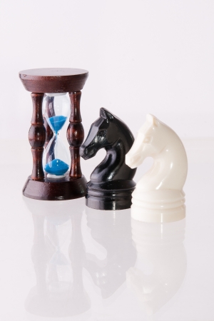 Black and white chess horses with sand-clock isolated on whiteの写真素材