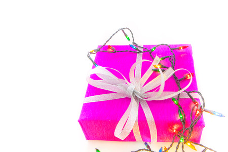 Christmas lights and packaged gift on white background with copy space