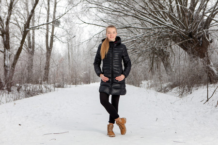 portrait of cute young woman in snow park in winterの写真素材
