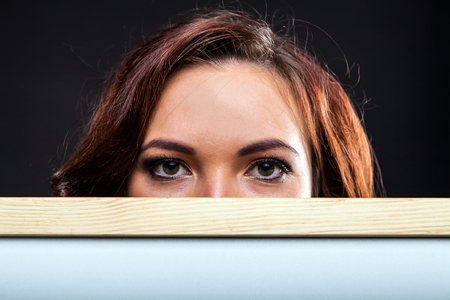 Portrait of attractive young woman holding office whiteboard on black background in studioの写真素材