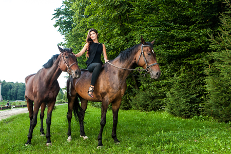Pretty young woman riding a brown horse outdoorの写真素材