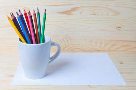 Color pencils in a mug and a piece of paperの写真素材