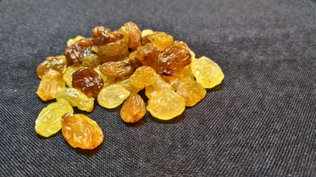 a small pile of yellow raisins on a dark background