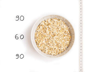 Oatmeal in white plate, centimeter and inscription on white background. Isolated on whiteの写真素材