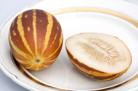 Mini cantaloupes cultivar called  Pineapple , one intact and one cutted, on a plateの写真素材