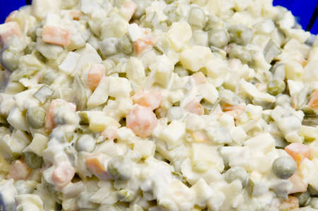 "Olivier" salad in a blue glass bowl as a backgroundの写真素材