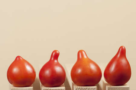 Four red tomatoes on a wooden tableの写真素材
