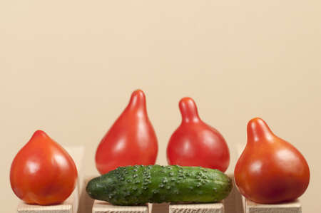 Four red tomatoes and cucumber on a wooden tableの写真素材