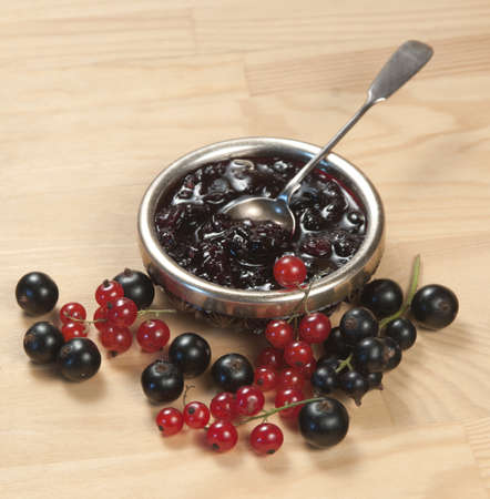 Black and red currant jam and berries on a wooden tableの写真素材