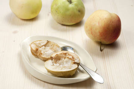 Baked apples on a plate and fresh applesの写真素材