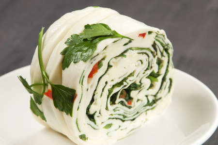 White cheese (brynza) roll with greenery and paprikaの写真素材