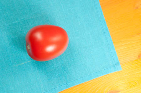 Beautiful tomato on a wooden table with blue napkin
