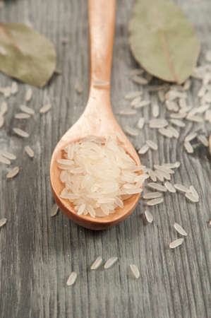 Rice in a wooden spoon and bay leavesの写真素材