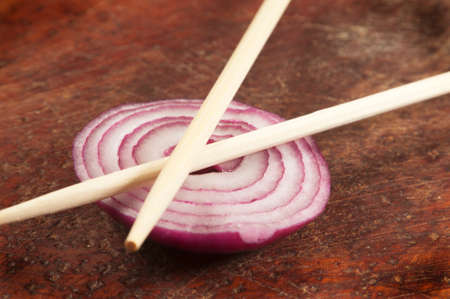 Still life with chopsticks and onion on a wooden boardの写真素材