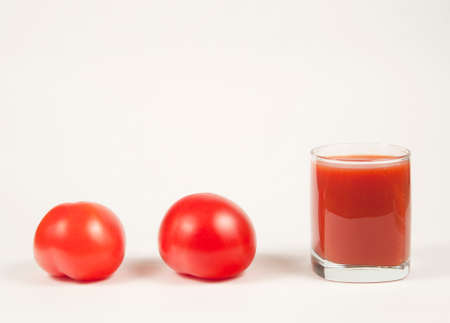 Tomato juice in a glass and two tomatosの写真素材
