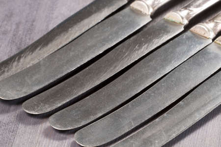 Old dinner knives on a wooden background
