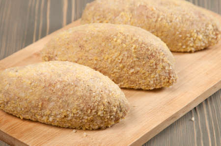 Fresh chicken cutlets prepared for frying on a boardの写真素材
