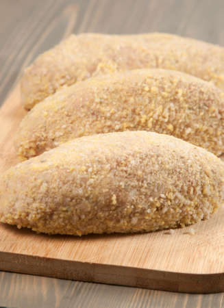 Fresh chicken cutlets prepared for frying on a boardの写真素材