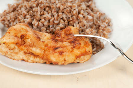 Chicken meat with buckwheat kasha on a white plate, closeup shotの写真素材