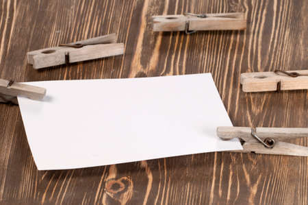 Old wooden clothes pins and blank paper on a timber board, close-upの写真素材