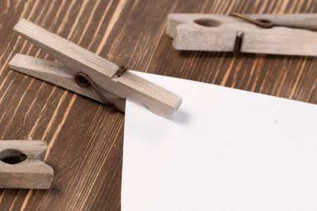 Old wooden clothes pins and blank paper on a timber board, close-upの写真素材