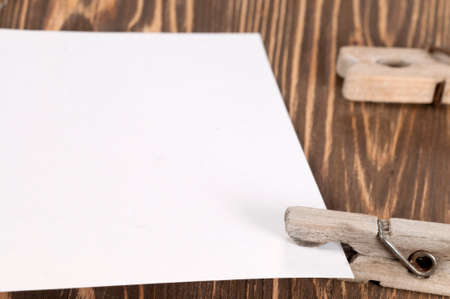 Old wooden clothes pins and blank paper on a timber board, close-upの写真素材