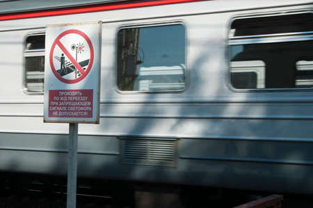 Prohibitive tablet and the passing train on the railway. Writing on a tablet "walking across the crossing when the traffic lights are red is prohibited!"の写真素材