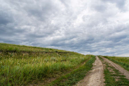 The steppe road ascends the mountain in cloudy weather with low cloud cover. Siberia