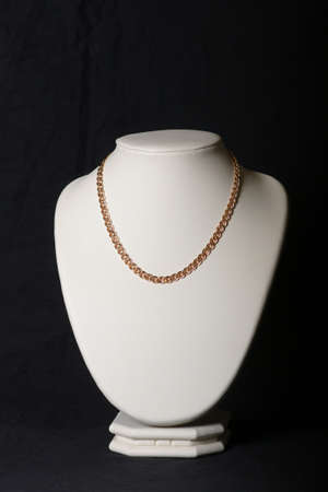 Beautiful golden necklace on a mannequin, isolated on blackの写真素材