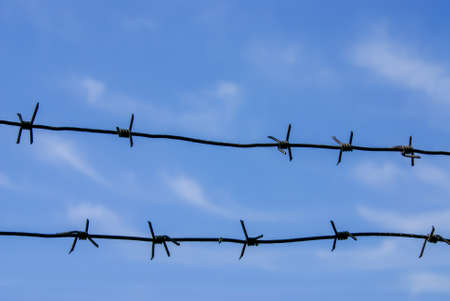 Close-up of barbed wire against the blue sky. Selective focus.
